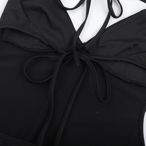 Close-up of black backless jumpsuit featuring tie-up halter neck detail on soft fabric