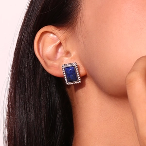 Dettaglio dell'orecchino vintage con lapislazzuli blu e bordo a perline d'argento su orecchio