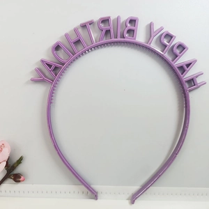 Macro detail of a purple Happy Birthday headband decoration on a white background