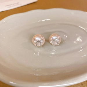 Detailed close-up of pink pearl stud earrings with silver metal bowknot design