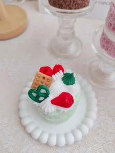 Detail of matcha green cake candle with strawberry, waffle, and cream toppings