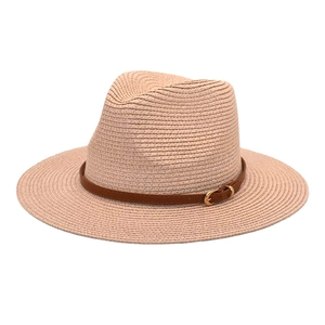 Close-up of pink woven Panama hat with brown leather belt and gold buckle detail