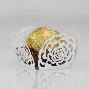 Macro view of white laser-cut rose hollow paper candy box with a gold foil chocolate