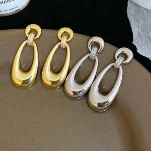 Detailed view of gold and silver plated oval drop earrings with micro-set zircon accents