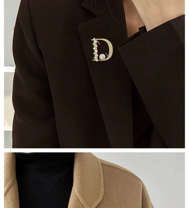 Detail einer goldenen Brosche Buchstabe D mit Kristallen und Perlen am Revers