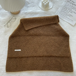 Detailed view of a brown knit scarf vest with chunky texture and decorative accessories