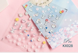 Detailed macro view of KX028 Pro bunny and cherry blossom nail art stickers on pink fabric