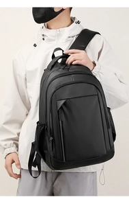 Close-up of durable black waterproof backpack with multiple zippers held by a model