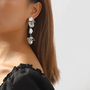 Detailed view of baroque pearl earrings with silver leaf petals on a female model