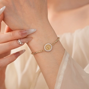 Détail macro du bracelet doré ajustable avec portrait religieux serti de zircons brillants