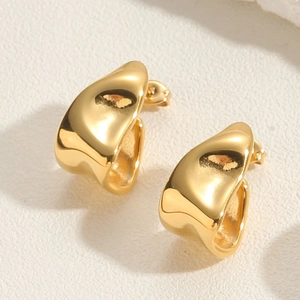 Detailed view of irregular hammered golden earrings with a polished metallic finish