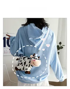 Detailed view of plush cow crossbody bag with black white spots and adjustable strap