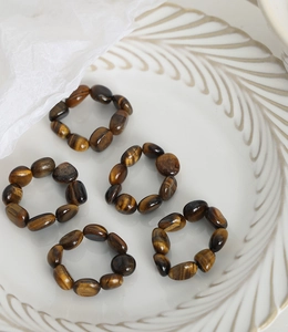 Detailed close-up of tiger eye stone beaded rings with unique luster on a ceramic tray