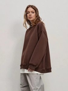 Detail view of oversized brown crewneck sweatshirt with dropped shoulders and ribbed cuffs