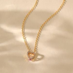 Detailed close-up of double heart pendant with pink stone and sparkling zircons