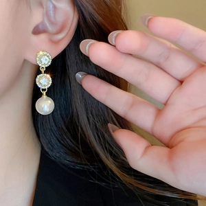 Elegant gold drop earrings with crystal circles and round pearls shown on model