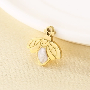 Close-up of golden insect pendant with white enamel details for jewelry making