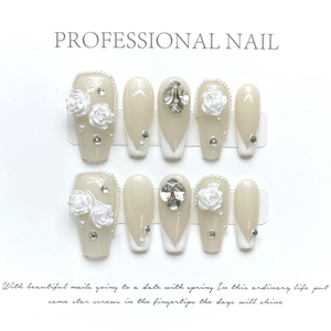Detail of handmade press-on nails featuring 3D embossed white roses and sparkling rhinestones