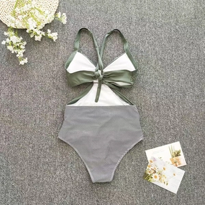 Close-up of olive green cutout swimsuit with striped bottom and bow detail