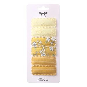 Detail of 6-piece yellow floral and lace fabric snap hair clips on display card