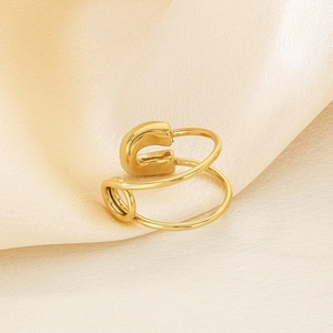 Detail of creative golden paperclip ring on soft champagne silk satin background