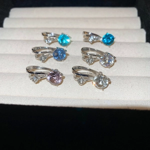 Gros plan de boucles d'oreilles argentées serties de cristaux bleus, roses et violets