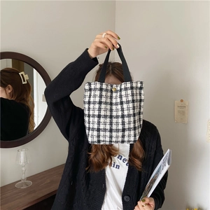 Close-up of black and white plaid wool handbag with golden buckle and durable strap