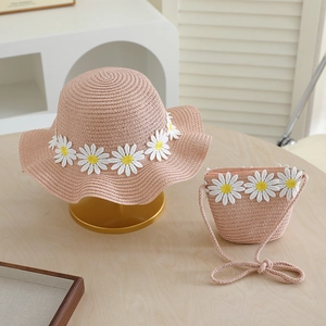Detailed view of pink straw sun hat and matching crossbody bag with daisy floral accents