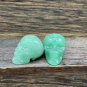 Detailed view of hand-carved green crystal skulls placed on a dark wooden surface