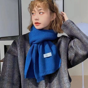 Detailed view of the soft knitted blue scarf with a small woven label on a model