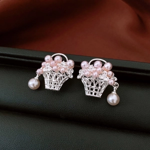 Détail de boucles d'oreilles panier argentées avec perles roses et blanches sur cuir