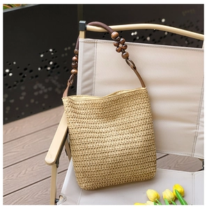 Detailed texture of woven straw bag with brown leather strap and dark wooden beads