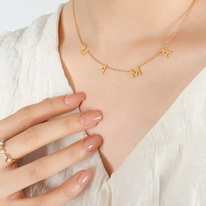 Élégant collier doré avec pendentif lettres MAMA porté par un mannequin en blanc