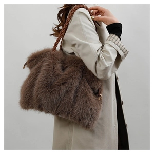 Detail of plush brown faux fur shoulder bag with woven texture handle on beige coat