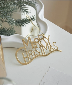 Close-up of golden Merry Christmas metallic lettering ornament with a hanging gold string