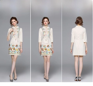 Detail of floral embroidery and sheer pink bow on beige retro A-line dress