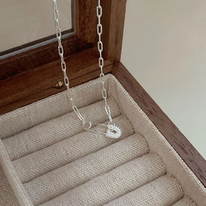 Close-up of 925 sterling silver safety pin pendant with pavé cubic zirconia in a jewelry box