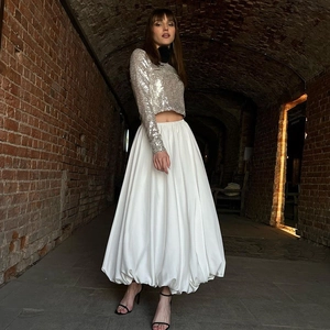 Detail van een witte geplooide maxi-rok gecombineerd met een zilveren lovertjes crop top