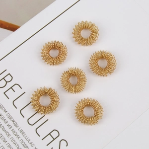 Detailed view of six golden spring finger massage rings on a white background