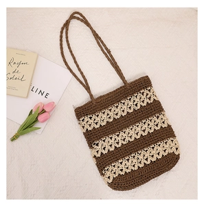 Close-up of woven straw tote bag featuring decorative beige floral cutout patterns
