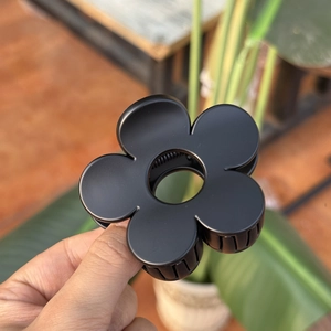 Gros plan de la pince à cheveux fleur noire mate 8cm avec détails du ressort