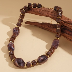 Détail de perles en résine marbrée et entretoises dorées sur collier vintage