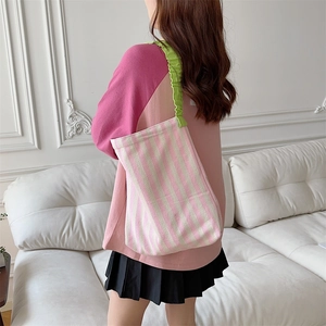 Detail of pink striped canvas tote bag featuring green ruffled ruched shoulder straps