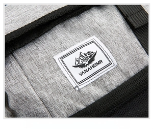 Macro shot of the VANAHEIMR woven label and grey textured fabric on the travel backpack