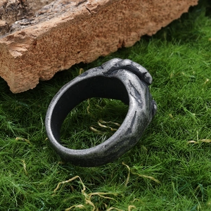 Vintage stainless steel handshake ring with an antique finish on green moss and bark background