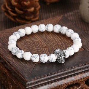 Men's agate bead bracelet with tiger eye and silver skull charm on wooden base
