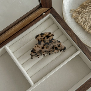 Detail of large acetate hair claw clip with light leopard print in a wooden jewelry box