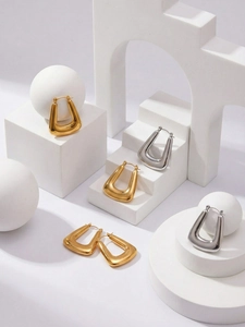 Detailed close-up of U-shaped geometric earrings in polished gold and silver finishes