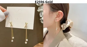 Detail of long gold tassel earrings with zircon X-shape studs and elegant pearls