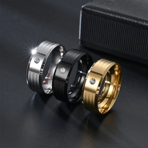 Close-up of stacked gold, silver and black stainless steel rings with single crystal stone